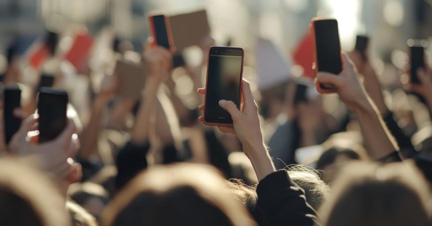 A group of people at a protest holding smartphones up in the air