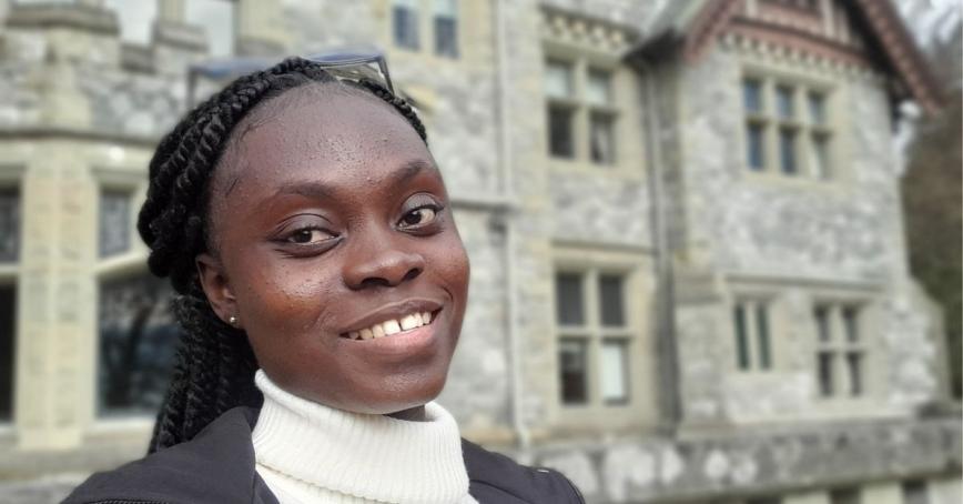 A smiling woman stands in front of Hatley Castle.