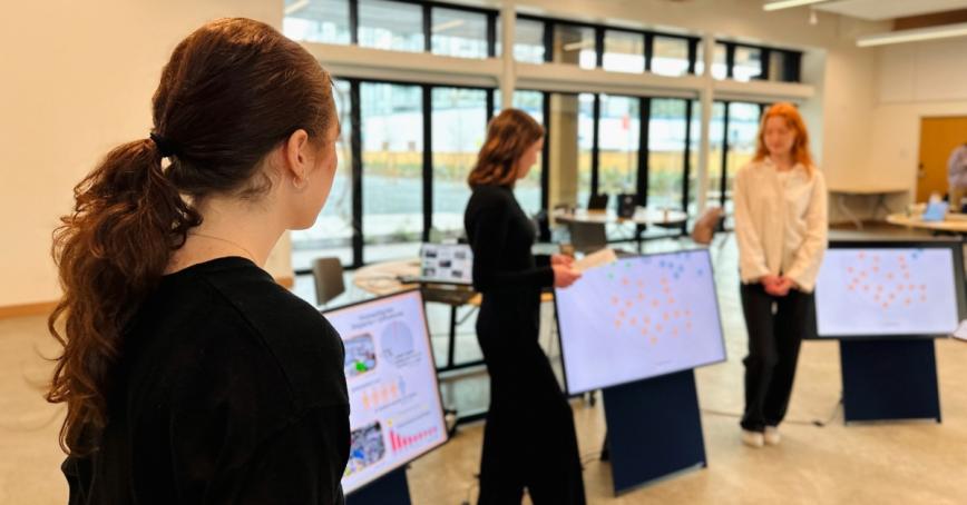 Three students presenting a "system map" inside the multi-purpose room at RRU John Horgan Campus