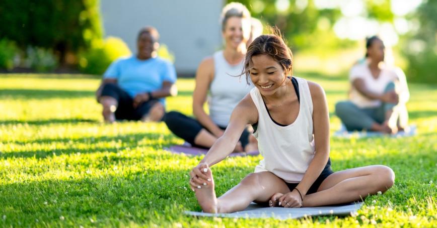 Stock photo of four people doing yoga outside on the grass