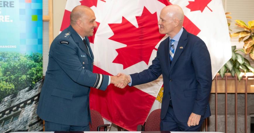 President Philip Steenkamp shakes hands with Major-General Jeannot Boucher, Commander of the Canadian Defence Academy, in front of a Canadian flag