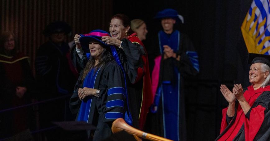 A doctoral graduate receives her sash on the convocation stage.