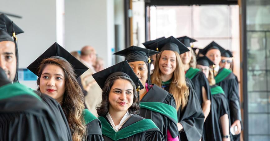 RRU graduates in regalia line up in the hallways to celebrate Convocation