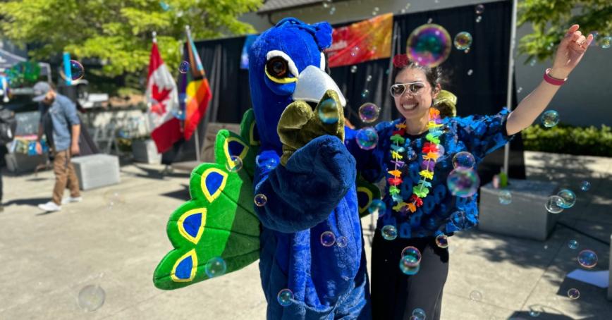A student dances with someone in a peacock costume