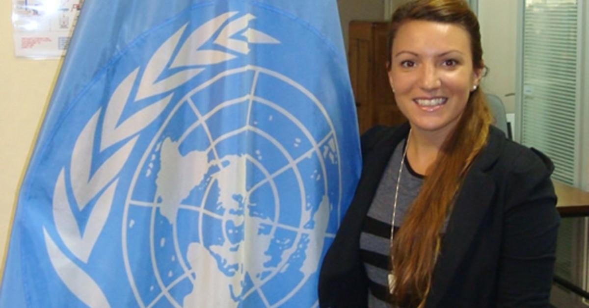 Jessica Hadjis standing next to a United Nations flag