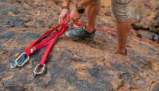 Person putting mountain climbing gear into rocks.