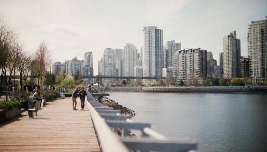 people along a boardwalk on the waterfront in a city.