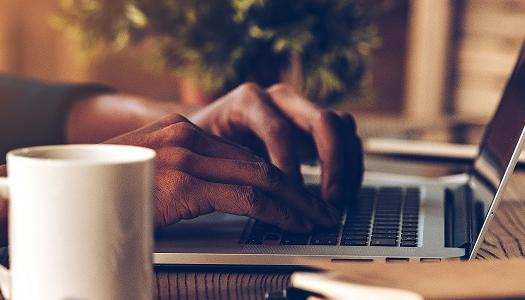 hands-typing-on-laptop-with-mug-in-foreground