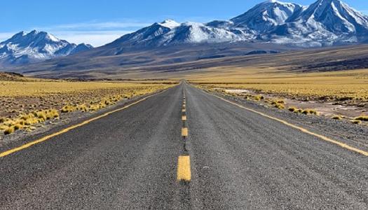 Road pointing to the horizon and the mountains in the distance.