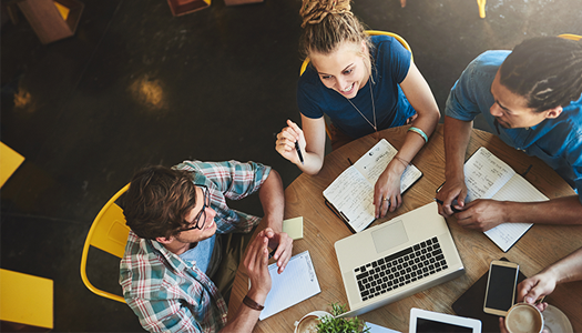 Three students working together at a round table.