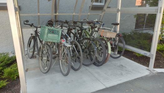 A number of bikes parked in a bike shelter.