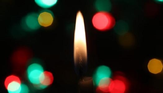 Picture of a candle light with colours blurred around it.