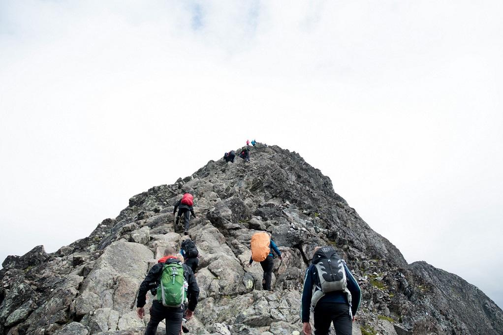 four people climbing steep hill