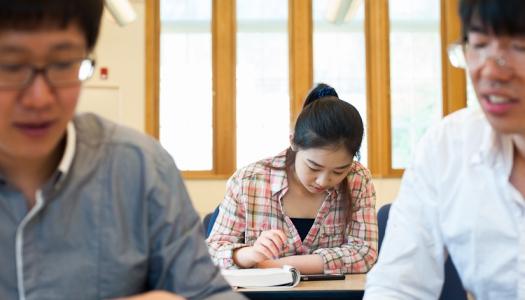 Three students reading at their desks inside a classroom