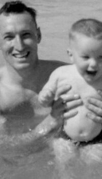 Bill Pratt as a child being held by his father in a swimming pool.