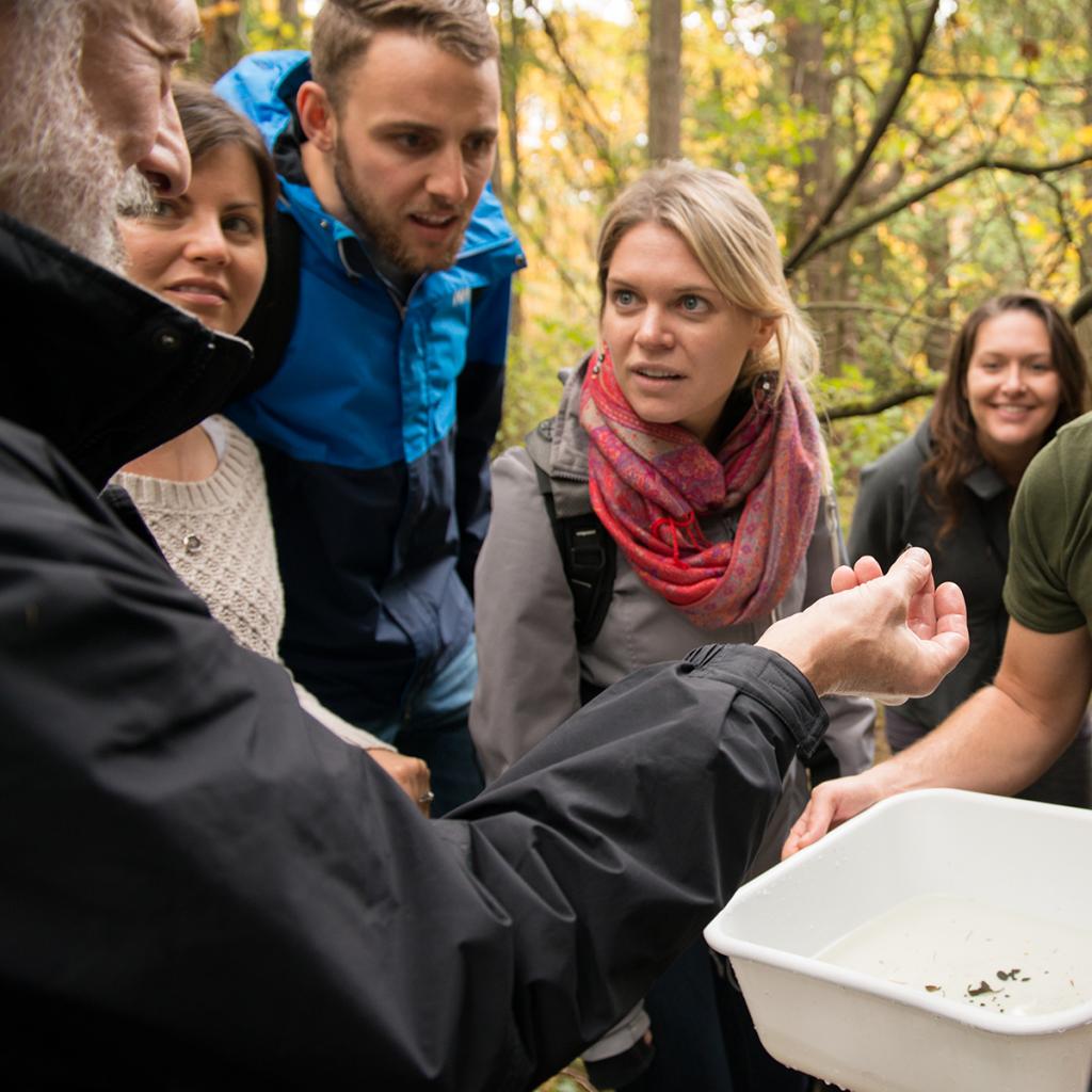 Students with professor outside holding seeds.