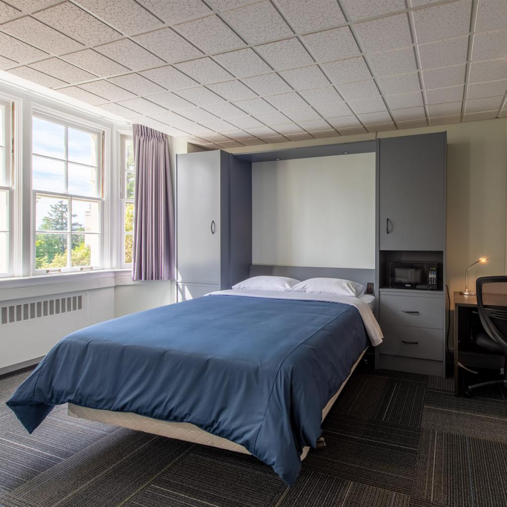 Room in the Nixon building with double bed and desk.