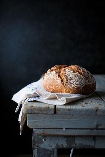 Round-loaf-of-bread-on-a-tea-towel-on-old-wooden-table