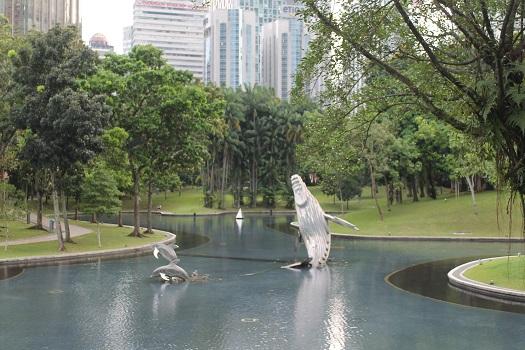 a-metal-whale-sculpture-in-a-pond-in-an-urban-park