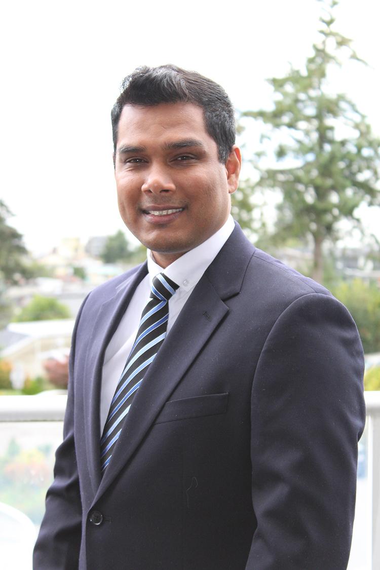 Mark Lokanan poses in front of a forested background.