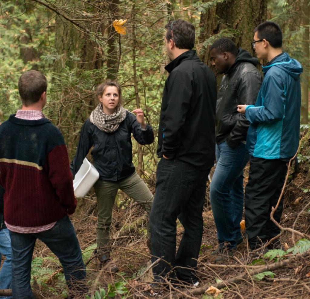 Students in the forest engaged in a class discussion.