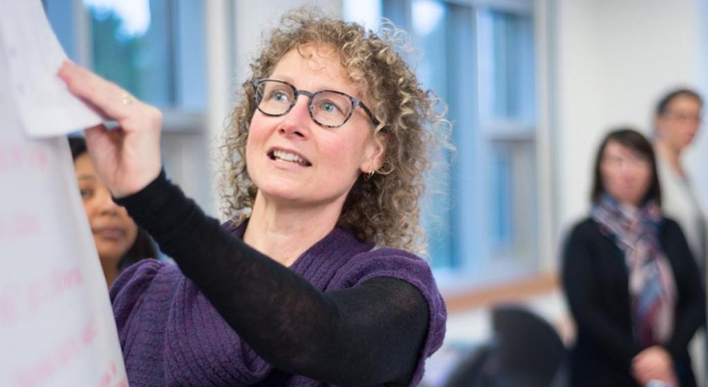 Student writing on a flipchart in front of their classmates