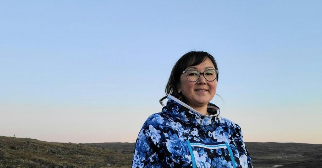 Photo of a woman in a blue sweater against a blue sky at sunset.