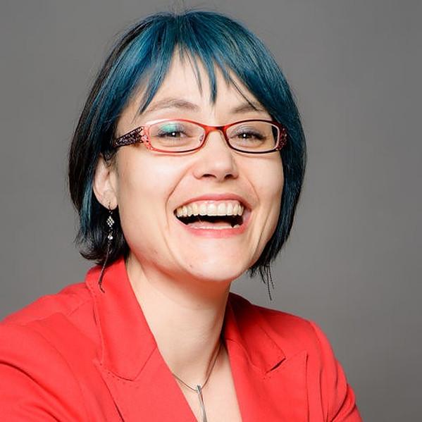 Jaigris Hodson, a woman with blue hair, smiles for her head shot.