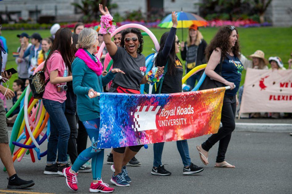 RRU students, staff and faculty walk behind an RRU Pride banner in the Victoria Pride Parade.