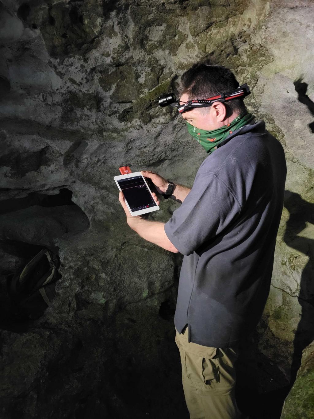 Person in a cave holding a device in hand