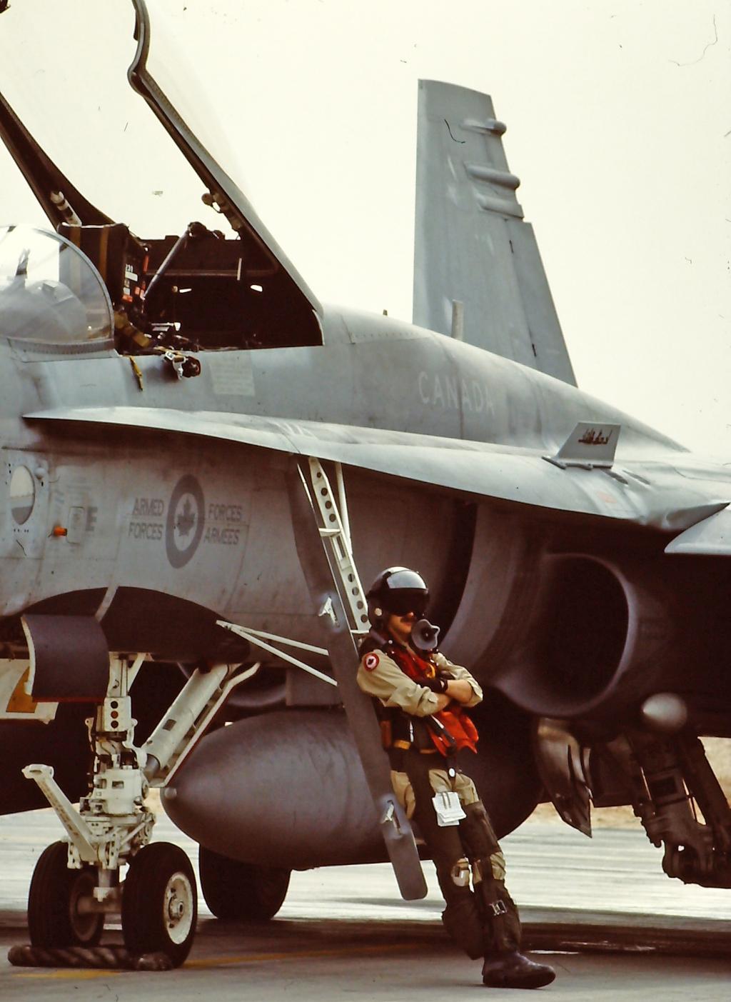Supervisor Rob Cox stands in front of a fighter jet in full flight gear