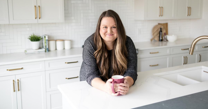 Woman poses while holding cup of coffee on countertop