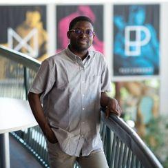 Taiwo Afolabi stands in front of a colorful background