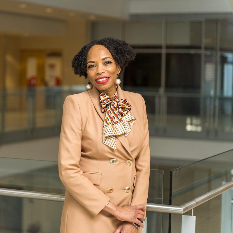 Prof. Andrea A. Davis at the top of a glassy staircase smiling.