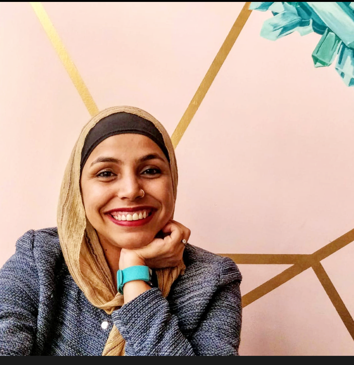 A picture of a smiling woman wearing a head scarf.