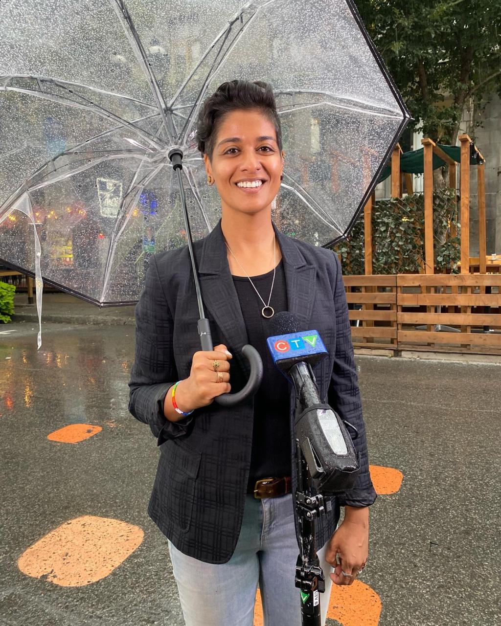Iman Kassam standing in downtown Montreal, holding an umbrella and smiling in front of a CTV microphone. 