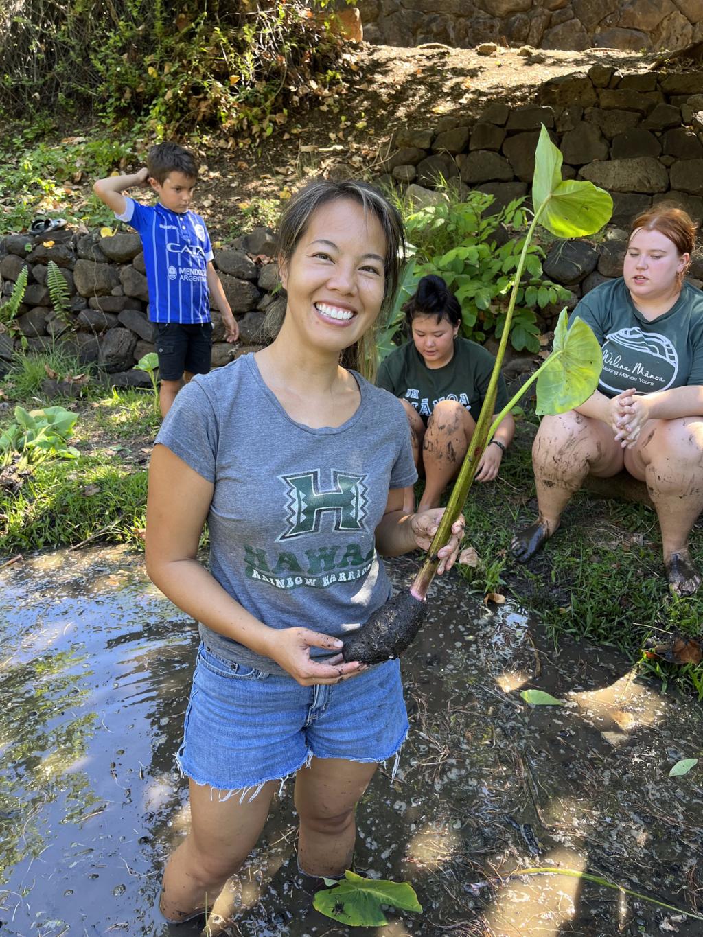 Vivian Giang holds a taro root, in front of community members in Hawai'i.