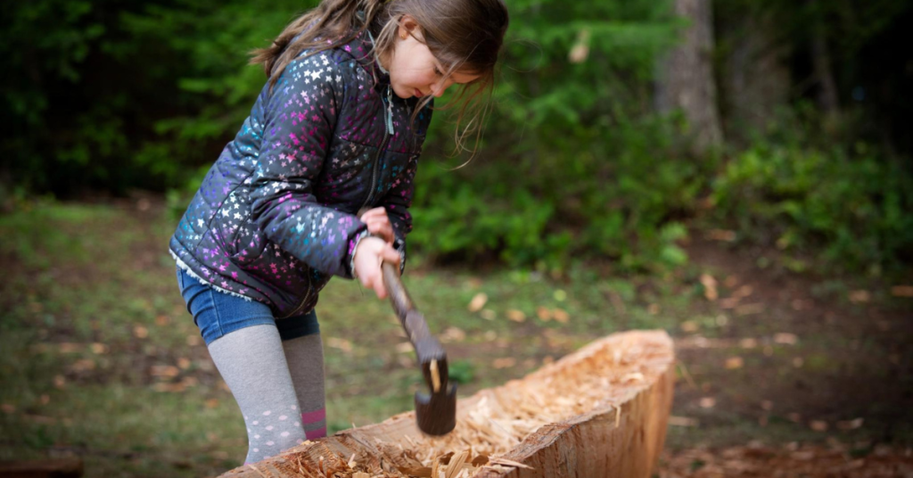 A child helps carve a dugout canoe.