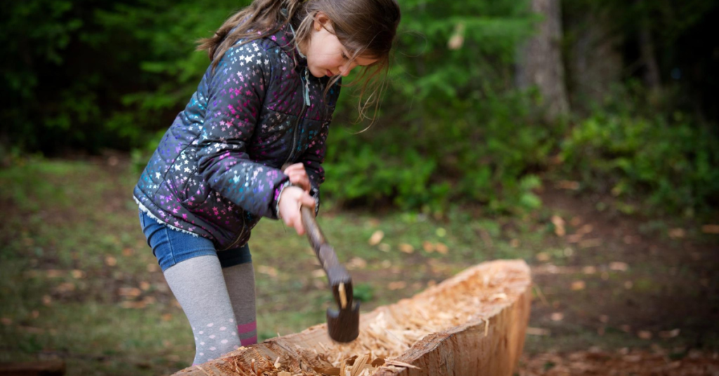 A child carves a canoe.