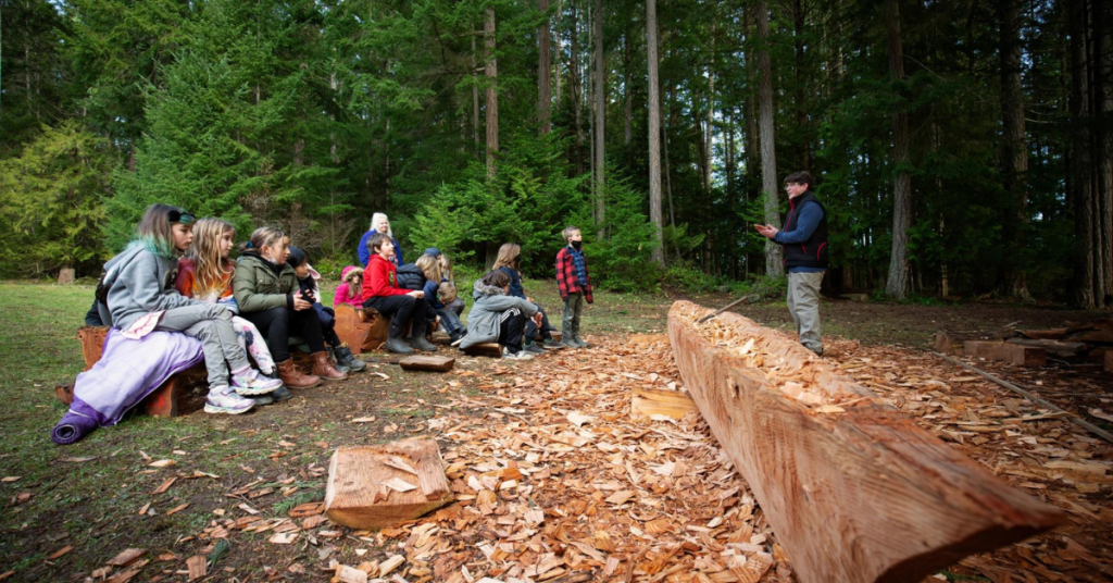 Canoe carver speaks to children about canoe.