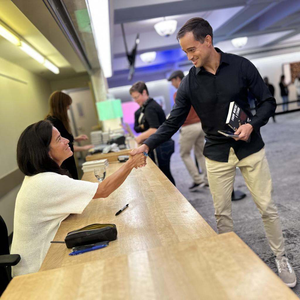 Jody Wilson-Raybould shakes hands with a delighted students who is clutching her book to have signed.