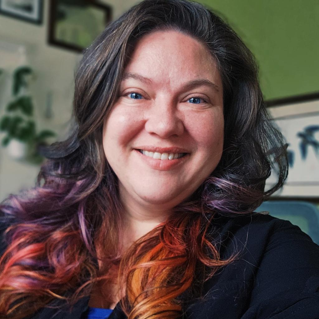 Gwen Hill smiles brightly, a tumble of multi-coloured hair falls on her shoulders.