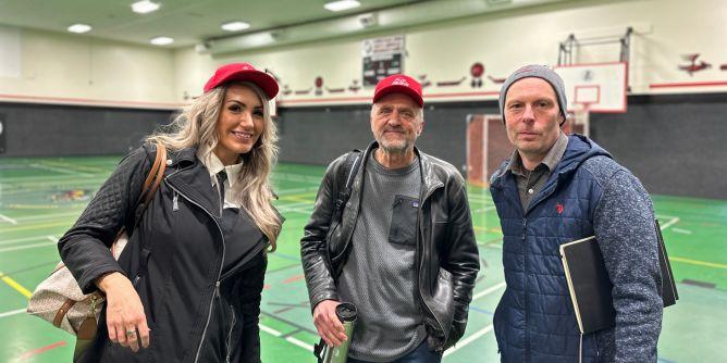 Three people smiling at the camera in a gymnasium.