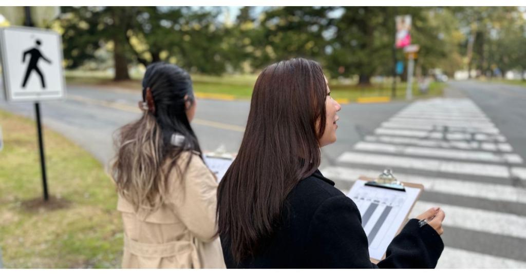 Students standing in front of crosswalk with their back to the camera.