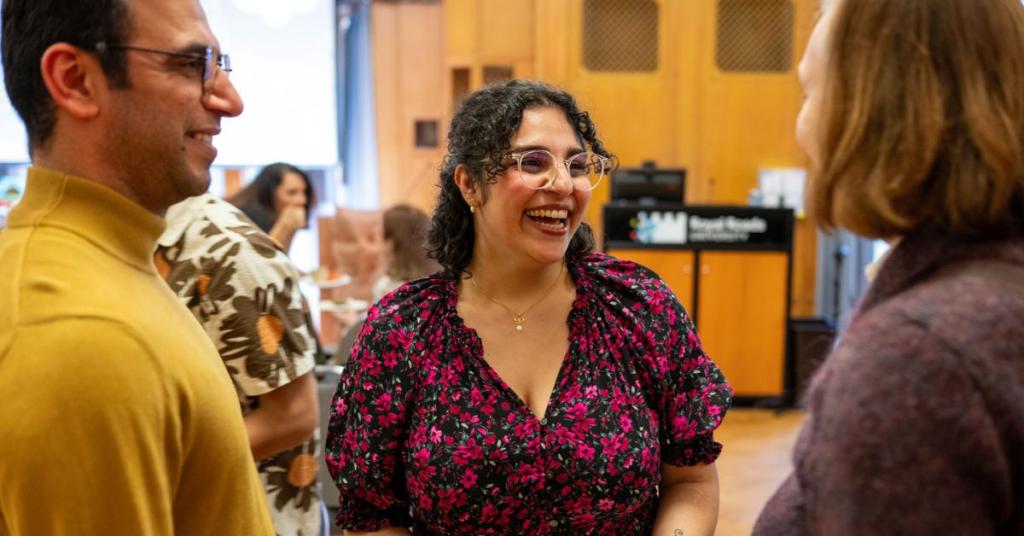 A woman laughs while interacting with two others at an indoor event
