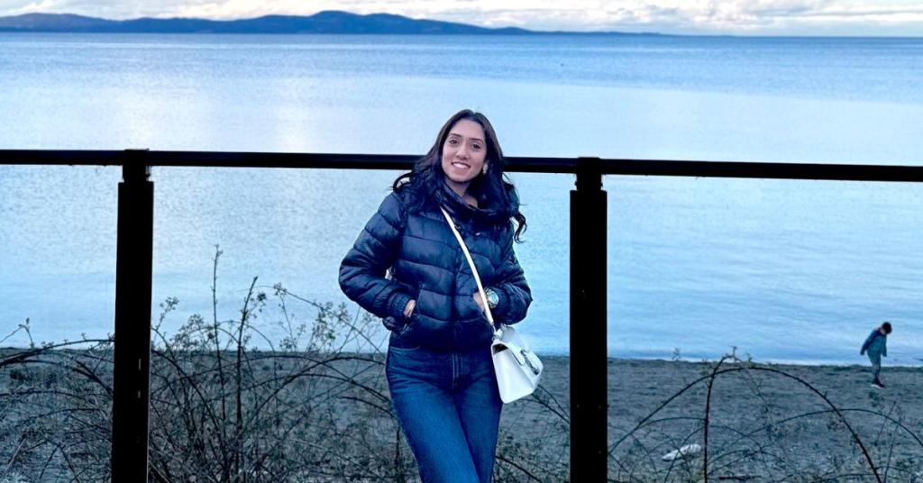 A woman poses for a photo in front of the ocean