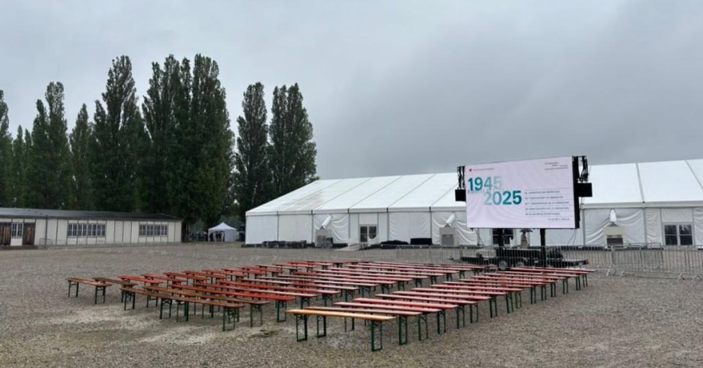 A view of the Dachau concentration camp 80-year liberation memorial set up with benches and a big screen
