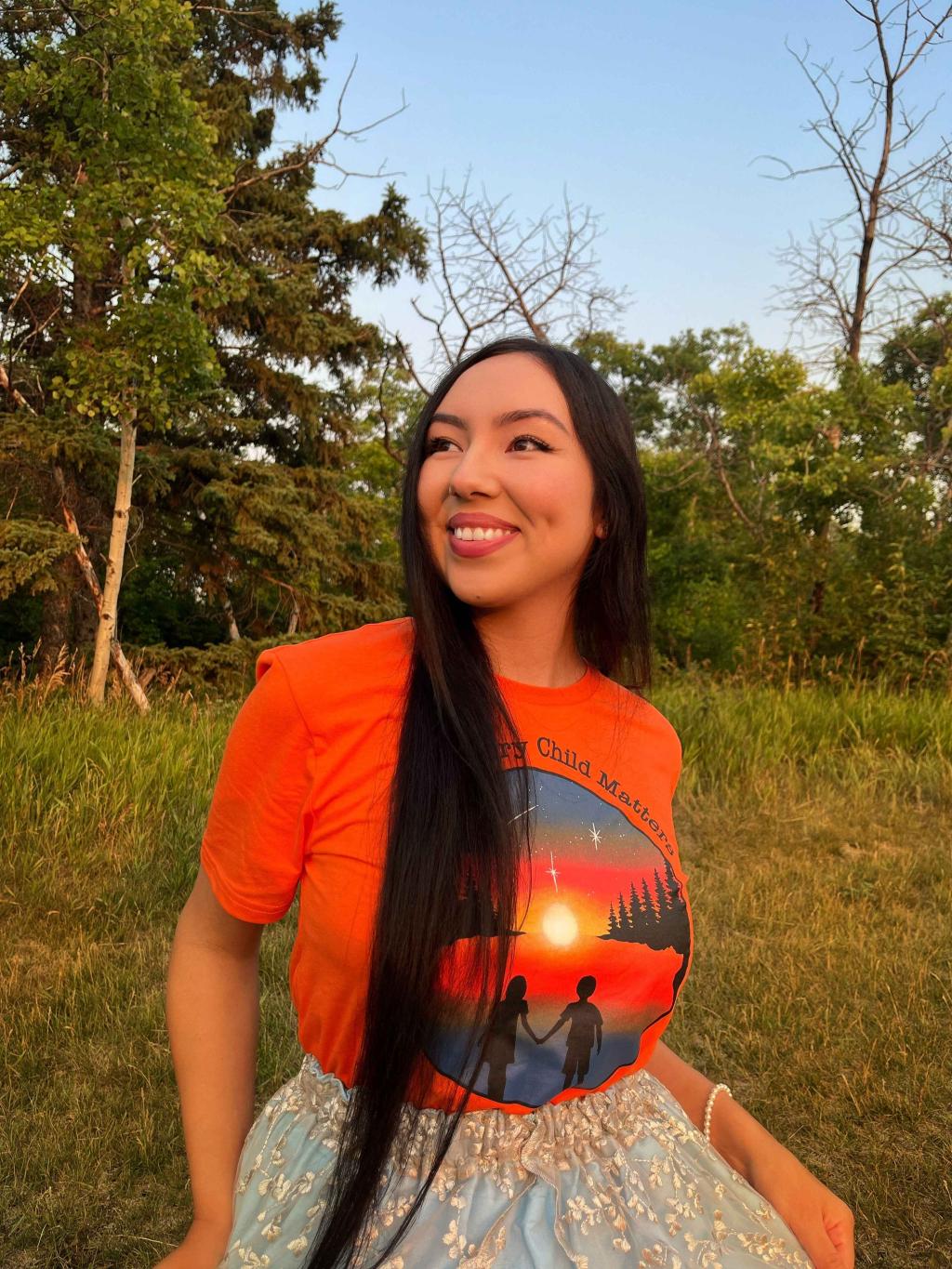 Brooklyn Rudolph poses wearing an orange shirt she designed