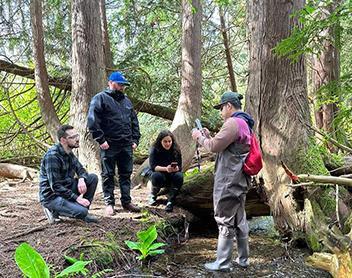 Environmental science students sitting together in the woods, engaged in discussion