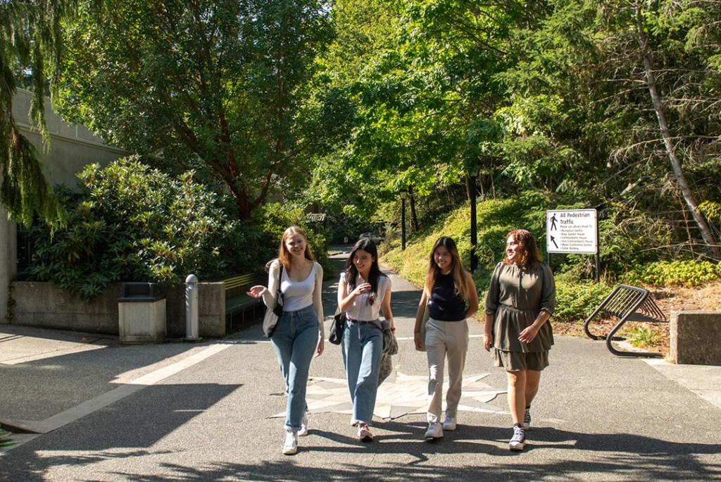 Four students walk through a paved path at Royal Roads University